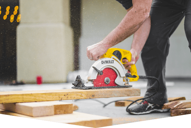 Carpenter working with a circular saw outside. Worker sawing wood board with electric circular saw. Close-up Carpenter working with a circular saw outside. Worker sawing wood board with electric circular saw. Close-up